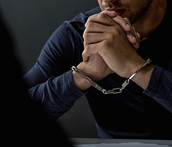 Male in handcuffs in a dark place