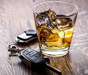 A tumbler glass with car keys on a table